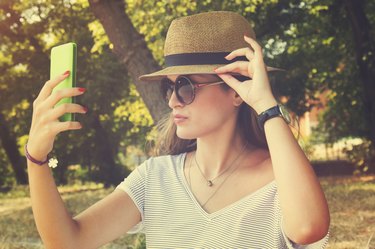 A young woman taking a selfie with her smartphone outdoors