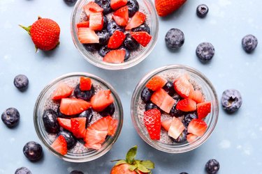 Three chia puddings in jars topped with fresh berries