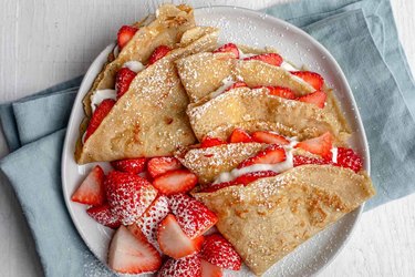 A plate of strawberry crepes teeming with fresh strawberries