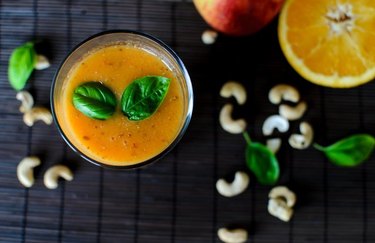 skin-boosting breakfast of Blood Orange and Cashew Smoothie on a black background with a halved orange and cashews
