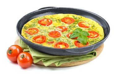 Fast Tomato-Basil Frittata in a skillet with tomatoes in front of a white background