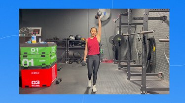 fit asian woman doing an offset waiter's carry with two dumbbells at the gym