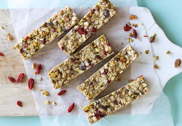 No-Bake Tahini Energy Bars on parchment paper on wooden cutting board over teal background.