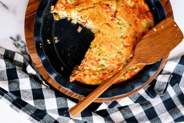 Oven Baked Omelet on a black plate with wooden spatula.