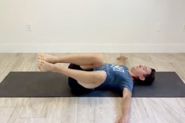 man doing the windshield wiper with reach stretch for core and back on a black mat