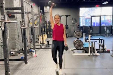 asian woman doing an offset waiter's carry with two dumbbells at the gym