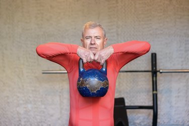 Man performing upright row with kettlebell.