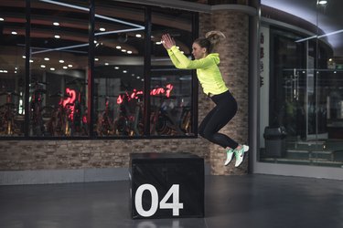 Woman doing box jump in gym.