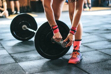 close up of a person securing a weight clip on barbell