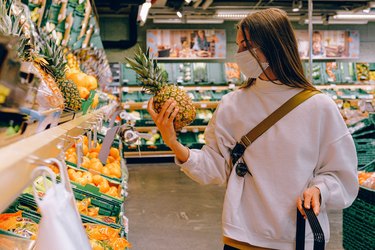 a woman wearing a mask while shopping for produce, to help prevent getting flurona