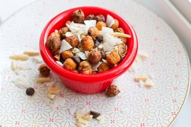Pumpkin Spice Roasted Chickpea Trail Mix in a red bowl with coconut flakes and chocolate chips