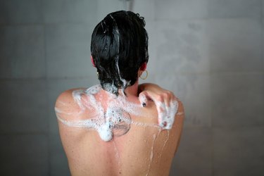 close-up shot of woman washing her back in the shower as a daily shoulder mobility exercise