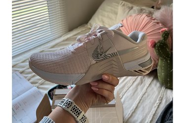 Writer holding pink and cream-colored Nike Metcon 8 shoe