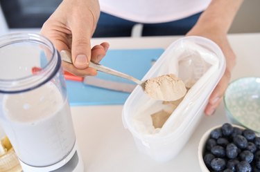 spooning protein powder for a smoothie