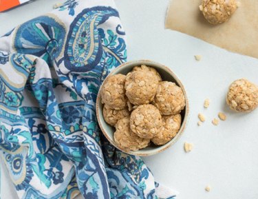 A bowl of no-bake nut butter crunchies placed next to a paisley patterned cloth