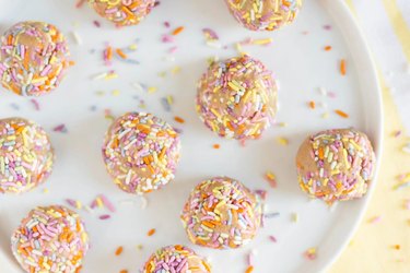 an overhead photo of vanilla cake batter bites with sprinkles on a white plate
