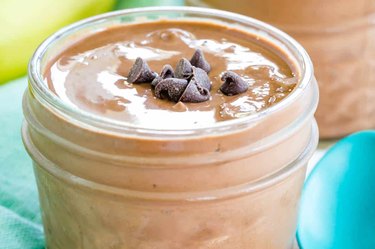 a closeup photo of Greek yogurt chocolate pudding in a jar with chocolate chips on top