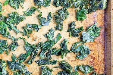 an overhead photo of homemade baked kale chips on a baking sheet as an example of a healthy late night snack