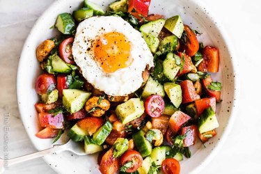 Healthy breakfast salad with tomatoes, avocado, cucumbers and a sunny side up egg