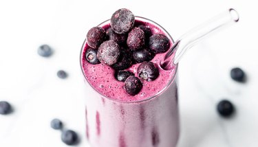 Beautiful blueberries top a purple smoothie in a glass