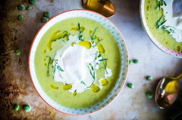 Chunky Pea and Leek Soup with Poached Eggs on marble table