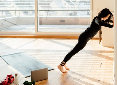 woman in black doing wall push-ups in a sunny room
