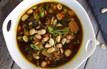 Bowl of tempeh soup, one of the best tempeh recipes with broccoli and peanuts in a white bowl