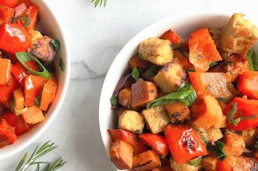 Sweet potato hash with red peppers ans spicy tempeh in a white bowl.