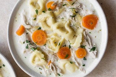 Instant Pot chicken and tortellini soup with carrots in a white bowl.