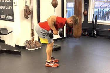 man doing the bent-over dumbbell row to work the back, arms, shoulders and core