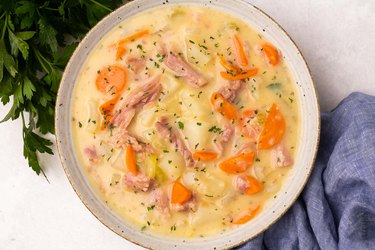 An overhead photo of a white bowl of Ham and Potato Soup