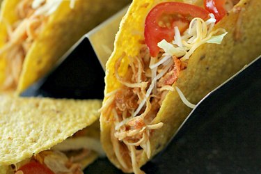 Three-Ingredient Slow Cooker Chicken Tacos topped with sliced pepper in a taco holder.