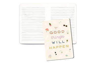 a photo of an open journal with lined pages behind the cover of the journal which says good things will happen in colorful font