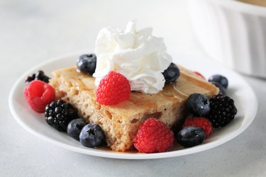 Baked Pancakes on a white plate with berries and whipped cream