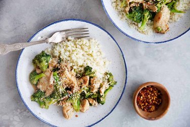Instant Pot Paleo Chicken and Broccoli served with rice in blue-lined white plate on marble gray countertop.