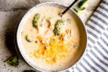 Instant Pot Broccoli Cheese Soup With Chicken in a speckled bowl on wood tabletop.