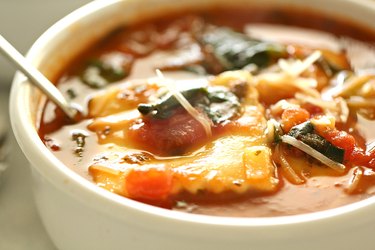 Bowl of ravioli soup with vegetables.