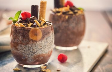 No-Cook Healthy Vegan Dark Chocolate Chia Pudding in glasses with banana and chocolate chips and a green-leafed garnish