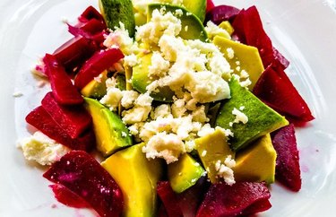 Beet, Avocado Salad With Crispy Goat Cheese Balls on a white plate.