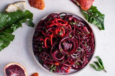 Spiralized Raw Beet Salad With Blood Oranges in a white bowl on white countertop/