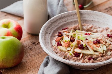 Slow cooker steel cut oats with apple and cranberries in a speckled bowl