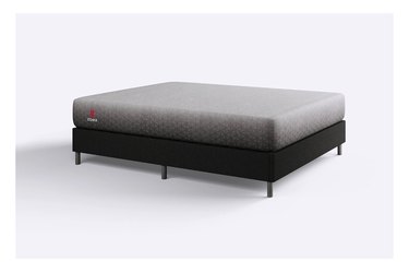 A gray mattress on a black bed from on a white background