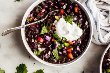 Cuban Black Bean Soup in a white bowl topped with sour cream.
