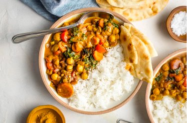 Instant Pot Chickpea Curry in a bowl with white rice and sliced naan on tabletop.