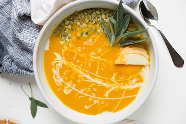Instant Pot Golden Glow Butternut Squash Soup in a white bowl over white countertop.