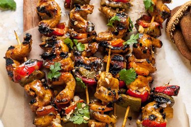 Chicken Satay Skewers with vegetables on wooden board