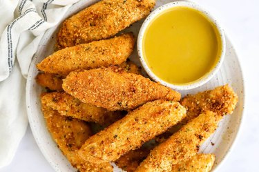 air fryer chicken tenders on a white plate with honey mustard on the side