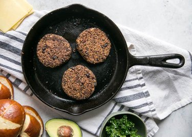 Quinoa Black Bean Burgers in cast-iron skillet on gray-and-white striped kitchen towel
