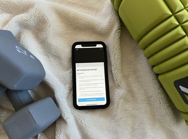 Photo of Movement Vault app on iPhone with dumbbells and a foam roller.