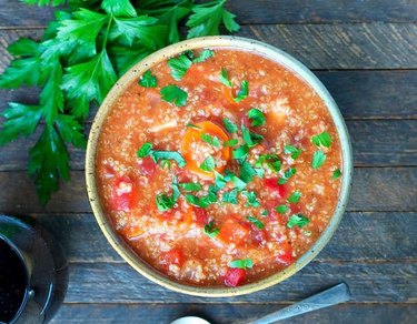 Slow Cooker Italian Chicken Soup with tomatoes and fresh parsley in a bowl on a wooden table.